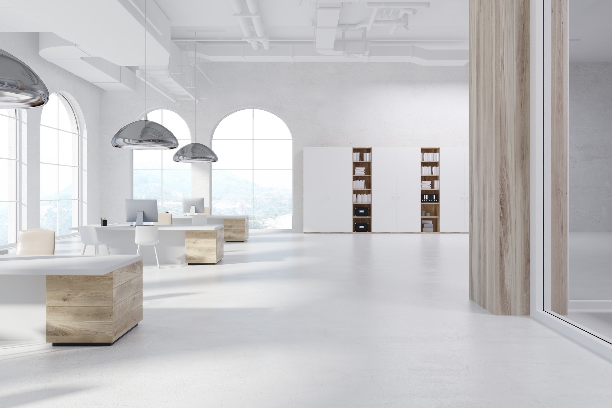 Modern office interior featuring spacious workstations with sleek desks, ample natural light from large windows, and stylish pendant lighting.